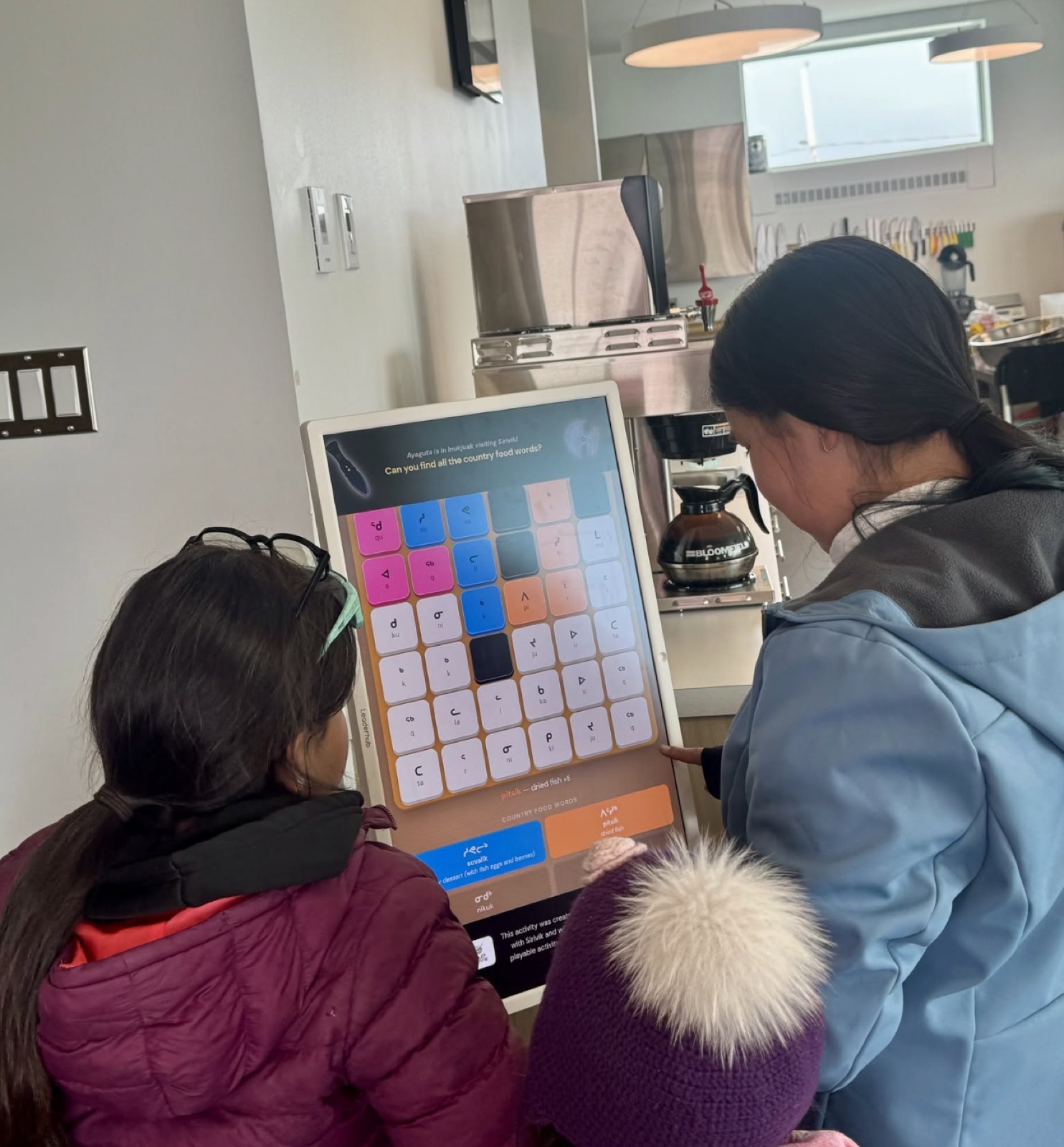 Children playing a word game on a kiosk